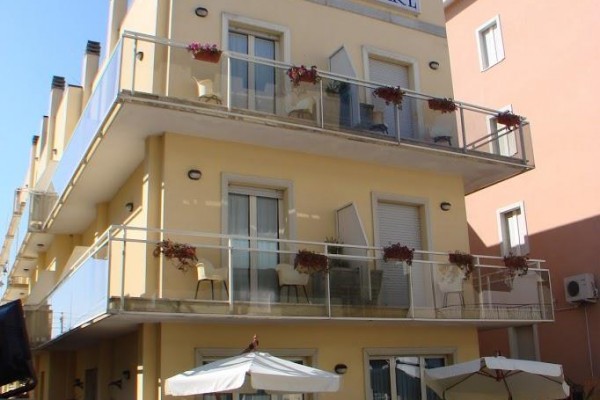 Trzypiętrowy żółty hotel z napisem 