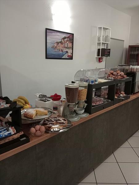Bufet śniadaniowy z pieczywem, płatkami, owocami i innymi produktami.