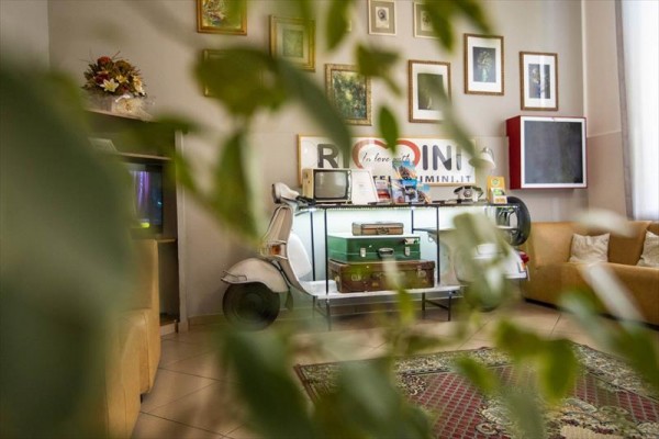Salon z dekoracjami vintage i połową skutera służącego jako półka z walizkami.
