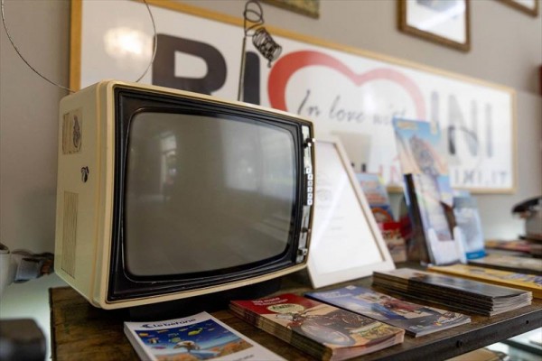 Stary telewizor wewnątrz przed reklamowym banerem i broszurami.
