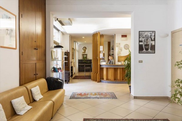 Recepcja hotelu z drewnianą ladą i fotelem na pierwszym planie.