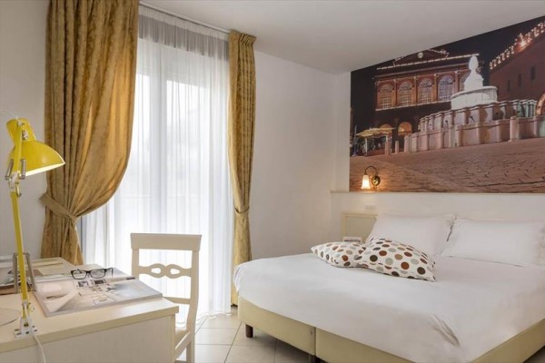Jasny pokój hotelowy z podwójnym łóżkiem i zdjęciem fontanny na ścianie.