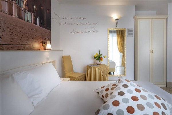 Nowoczesny pokój hotelowy z żółtymi akcentami i dekoracyjnym malowidłem na ścianie.