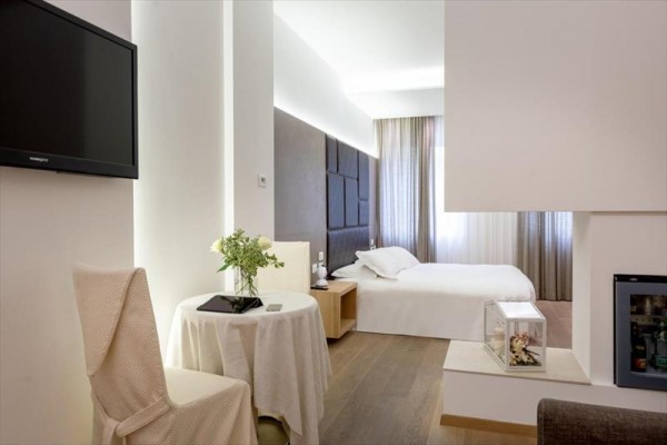 Nowoczesny pokój hotelowy z podwójnym łóżkiem, telewizorem i stolikiem z kwiatami.