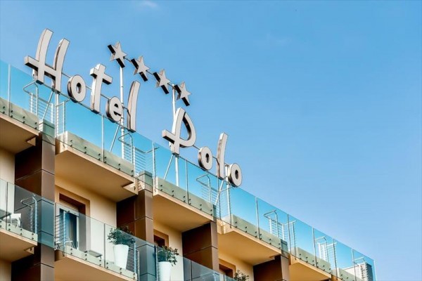 Budynek hotelu Polo z czterema gwiazdkami i szklanymi balustradami na balkonach.
