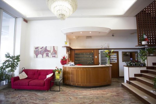 Hotelowa recepcja z czerwoną kanapą i schodami.