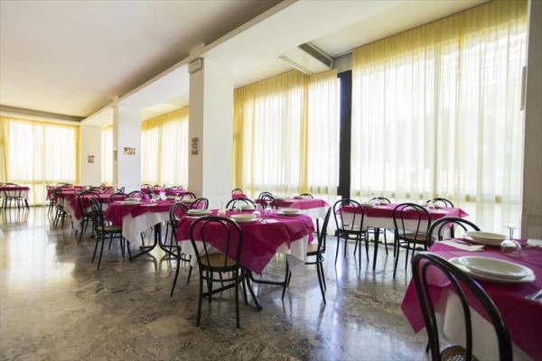 Restauracja z różowymi obrusami i szklanymi taflami przy oknach.