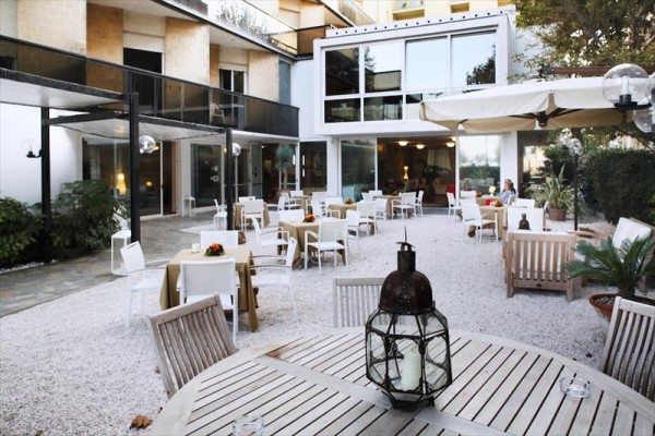 Zewnętrzny taras restauracji z drewnianymi meblami i stołami z obrusami.