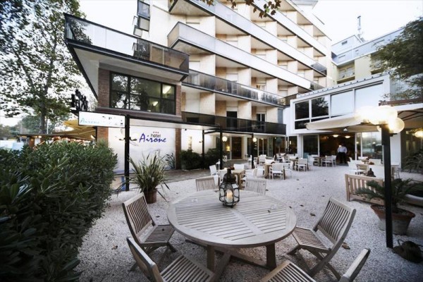 Nowoczesny hotel z zewnętrznym tarasem i okrągłymi drewnianymi stołami.