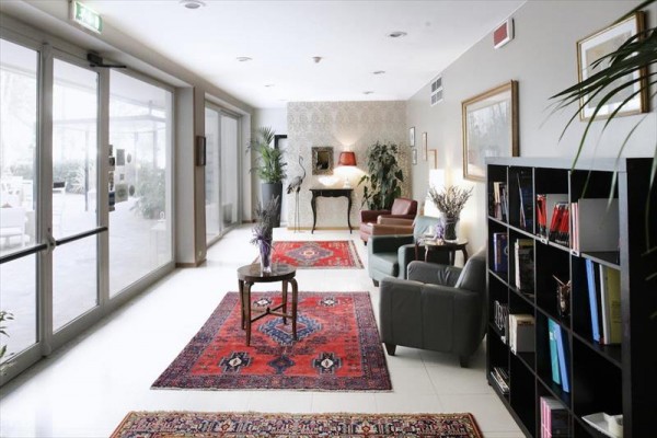 Elegancki hol hotelowy z czerwonymi dywanami, fotelami i biblioteczką.