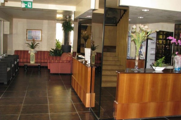 Recepcja hotelowa z fotelami i kwiatami.