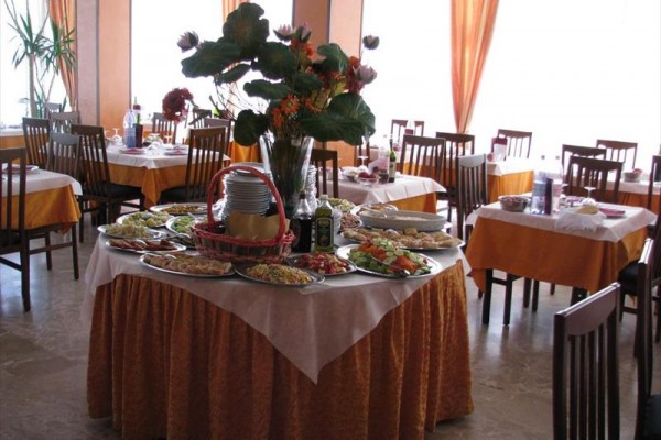 Okrągły stół z przekąskami i kwiatami w jasnej restauracji.