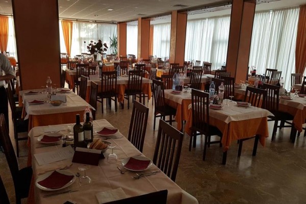 Przytulnie oświetlona restauracja z nakrytymi stołami gotowymi na przyjęcie gości.