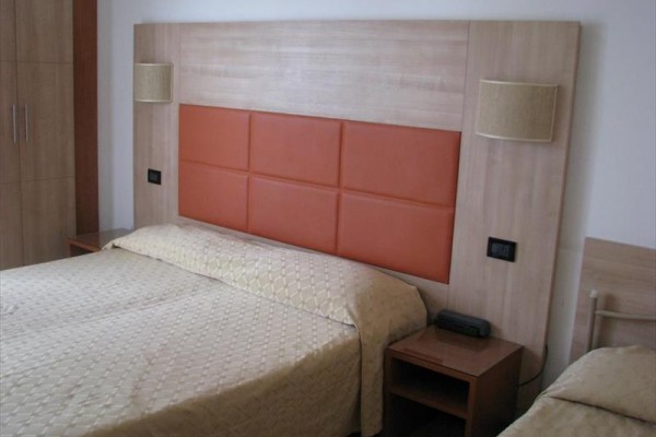 Łóżko z pościelą w pokoju hotelowym z drewnianym zagłówkiem.