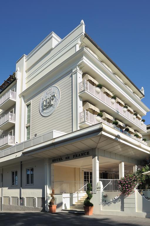 Jasny nowoczesny hotel z ozdobnymi balkonami i kwiateniem.