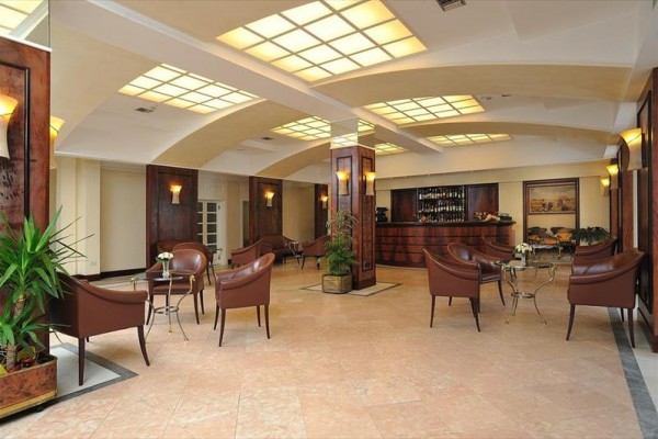 Elegancki salon hotelowy z skórzanymi fotelami i barem.