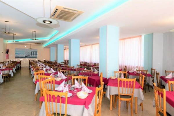 Restauracja z nakrytymi stołami w pastelowym wnętrzu.
