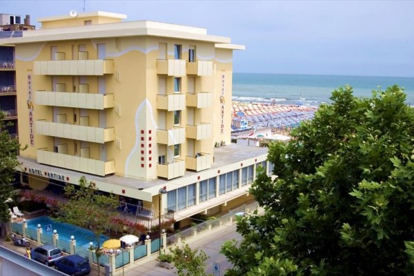 Duży hotel w nadmorskim kurorcie z ogrodem i widokiem na plażę.