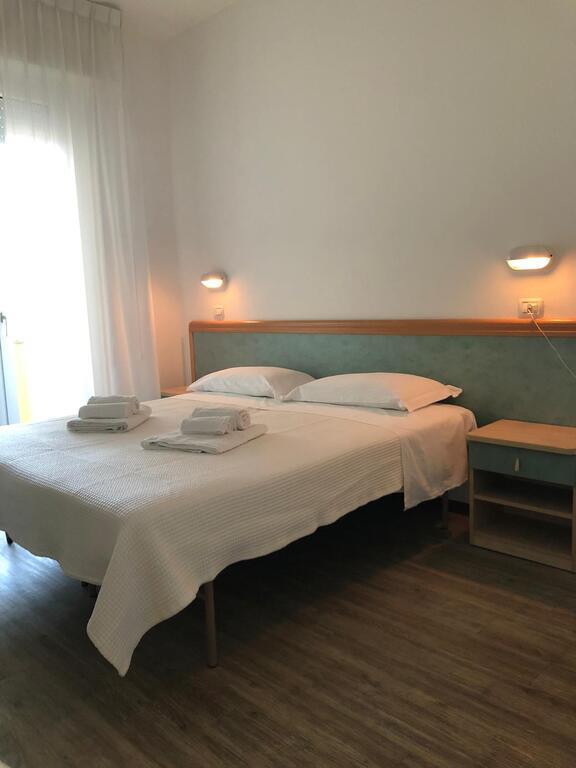 Łóżko podwójne w prostym pokoju hotelowym z pościelą i ręcznikami.