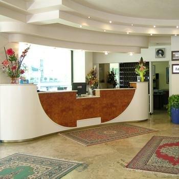 Recepcja hotelu z ozdobnymi dywanami i dekoracjami kwiatowymi.