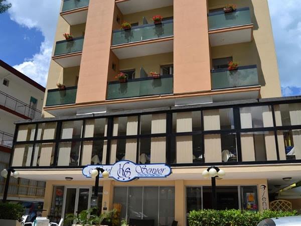 Budynek hotelu z kilkoma balkonami i kwiatami na żółtej elewacji.