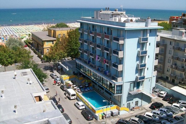 Niebieski hotel z basenem w pobliżu plaży i morza.