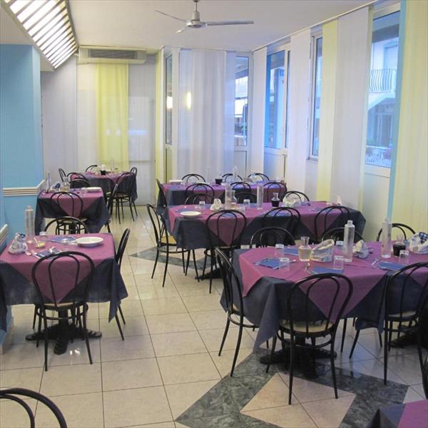 Restauracja z okrągłymi stołami i krzesłami, przygotowana do posiłku.