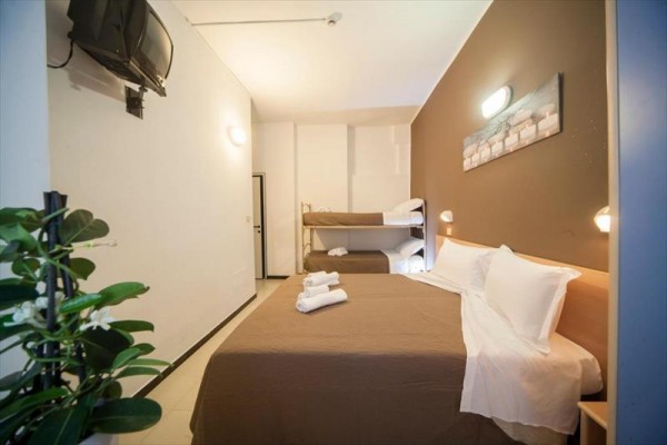 Pokój hotelowy z łóżkiem małżeńskim, łóżkiem piętrowym, telewizorem i roślinami doniczkowymi.