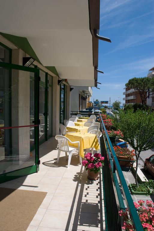 Długi balkon z białymi krzesłami i żółtymi obrusami obok kwiatowej dekoracji.