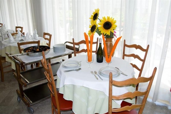 Stół z kwiatami, butelką wina i nakryciem dla dwóch osób w restauracji.
