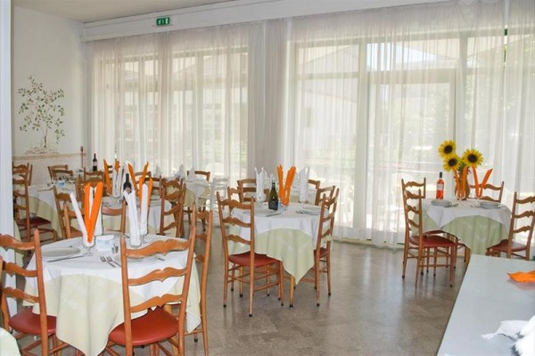 Restauracja z okrągłymi stołami ozdobionymi serwetkami i słonecznikami.