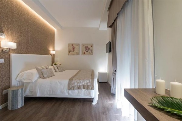 Nowocześnie urządzona sypialnia hotelowa z podwójnym łóżkiem i dekoracjami w neutralnych kolorach.  