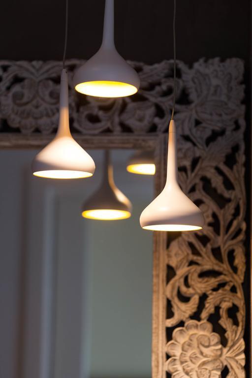 Białe wiszące lampy przed ozdobnym lustrem.