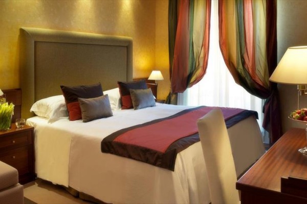 Luksusowy pokój hotelowy z dużym łóżkiem i kolorowymi zasłonami.