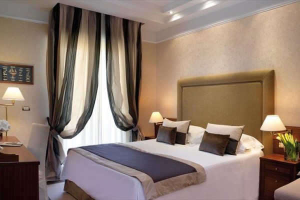 Luksusowy pokój hotelowy z dużym łóżkiem, stylowymi zasłonami i lampkami nocnymi.