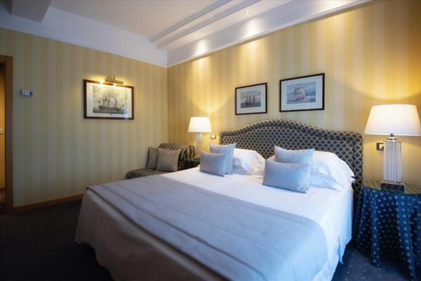 Elegancki pokój hotelowy z dużym łóżkiem i lampami.
