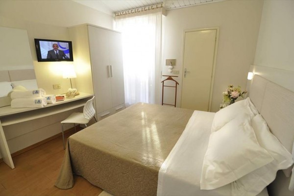 Nowoczesny pokój hotelowy z podwójnym łóżkiem, telewizorem i biurkiem.