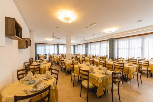 Przestronna restauracja z obrusami na stołach i drewnianymi krzesłami.