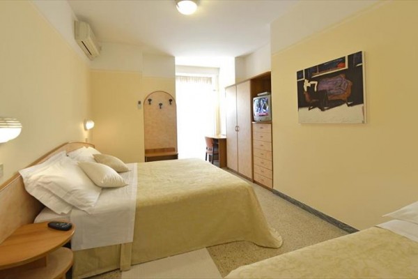 Pokój hotelowy z łóżkiem małżeńskim, telewizorem i jasnymi meblami.