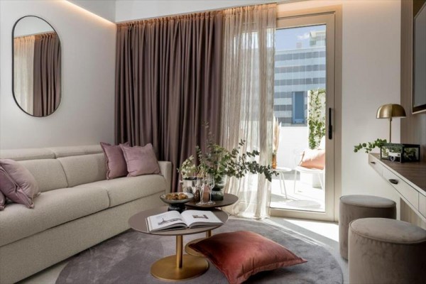 Jasny salon z beżową kanapą, okrągłym stolikiem i wyjściem na taras.
