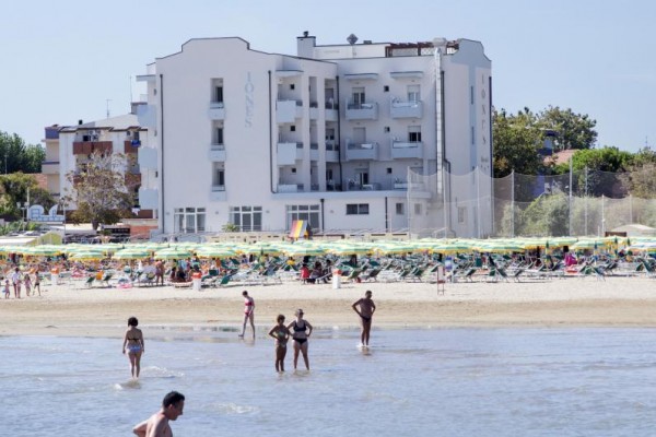 Plaża z ludźmi i hotel w tle.