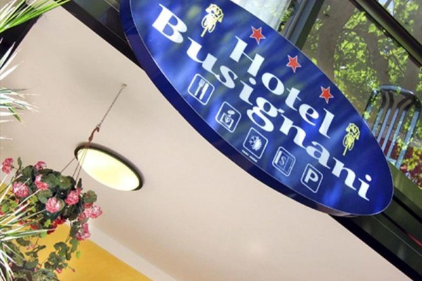 Niebieski szyld z napisem Hotel Busignani i czterema piktogramami.