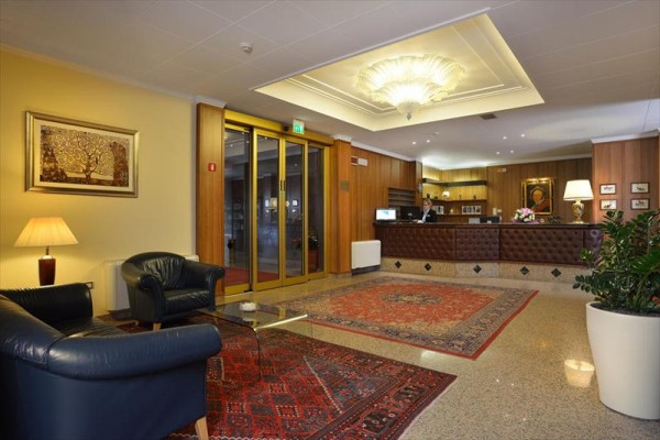 Recepcja hotelu z skórzanymi fotelami i dywanem na podłodze.