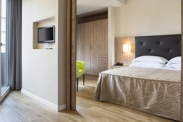 Pokój hotelowy z łóżkiem, telewizorem na ścianie i szafą.