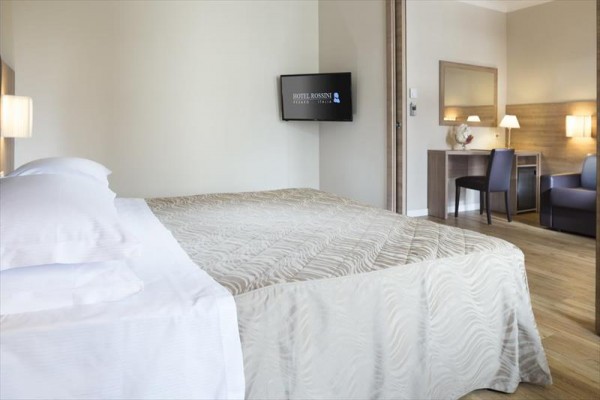 Nowoczesny pokój hotelowy z podwójnym łóżkiem, telewizorem i biurkiem.