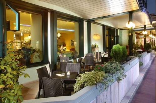 Zewnętrzny taras restauracji z wiklinowymi krzesłami i roślinami.