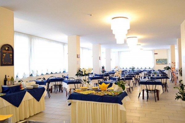 Jasna restauracja z niebiesko-białymi obrusami i stolikami przygotowanymi dla gości.