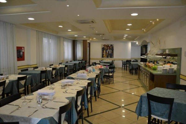 Przestronna restauracja z przygotowanymi stołami i bufetem.