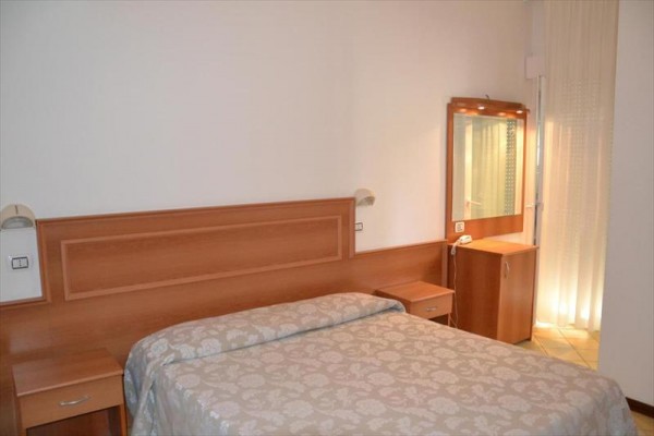 Pokój hotelowy z podwójnym łóżkiem, toaletką i zasłonami.