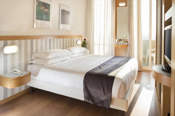 Nowocześnie urządzona hotelowa sypialnia z podwójnym łóżkiem i balkonem.